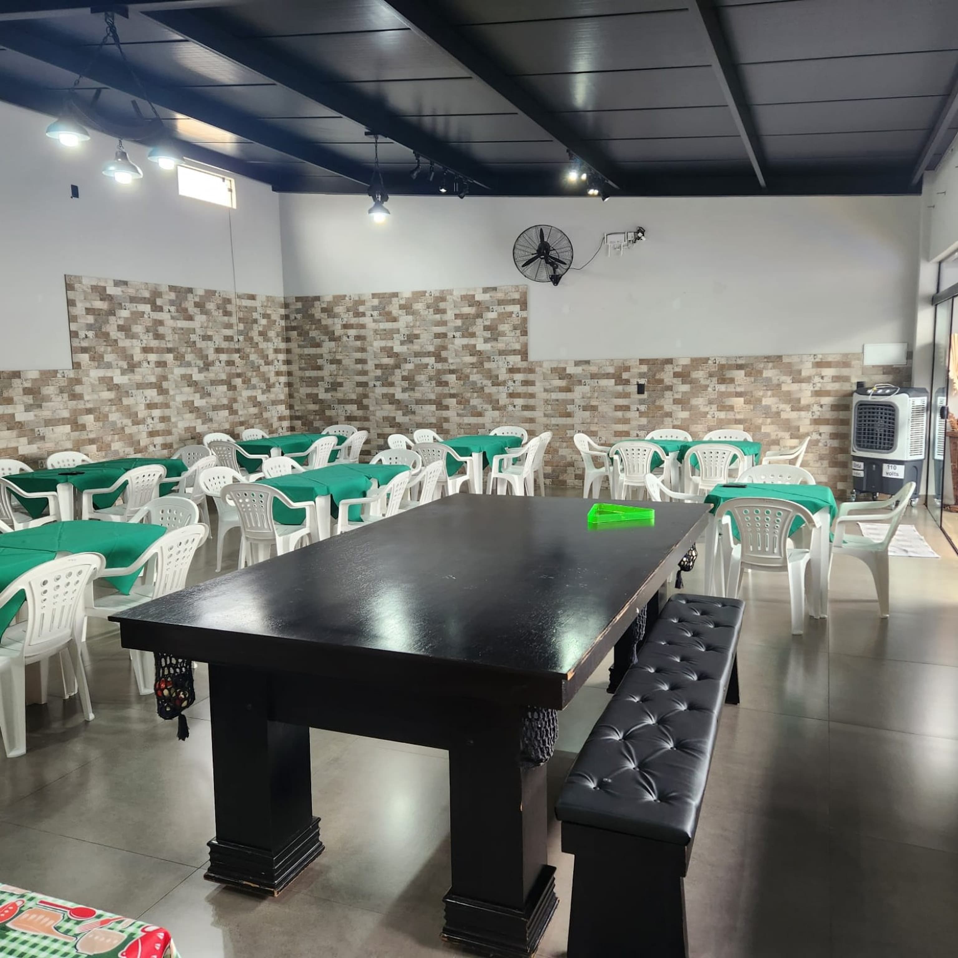 Salão coberto do Athenas Eventos com mesas, cadeiras e mesa de sinuca